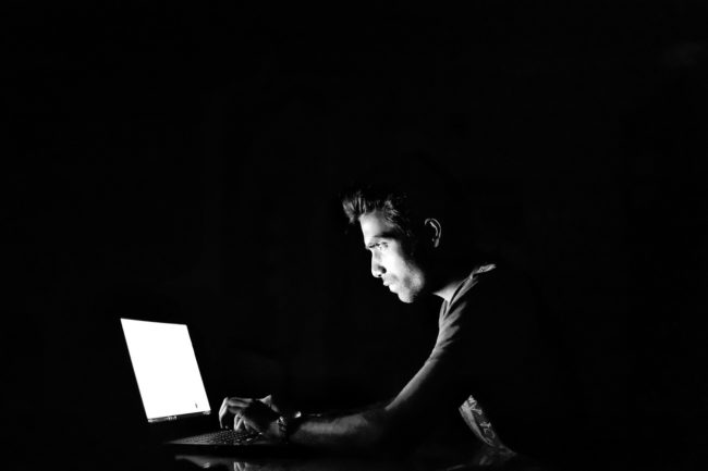 Mann am Computer vor schwarzem Hintergrund. EXIT-Deutschland